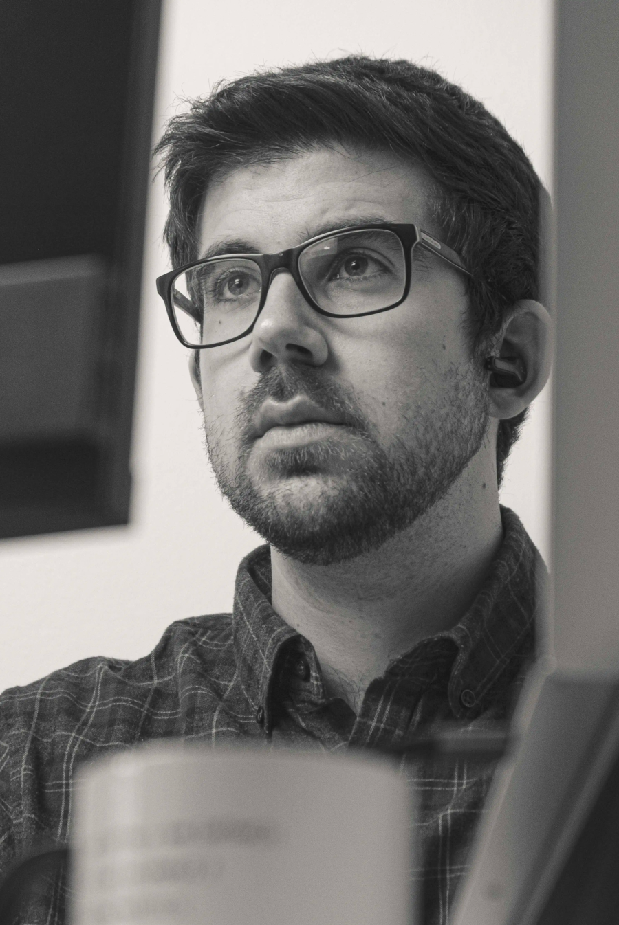 Black and white portrait of Manuel wearing glasses and looking thoughtful.